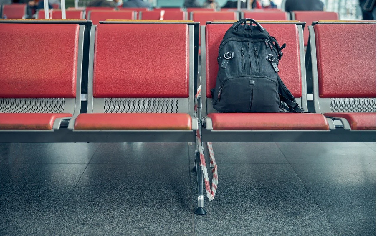 Black backpack left on a row of red airport seats