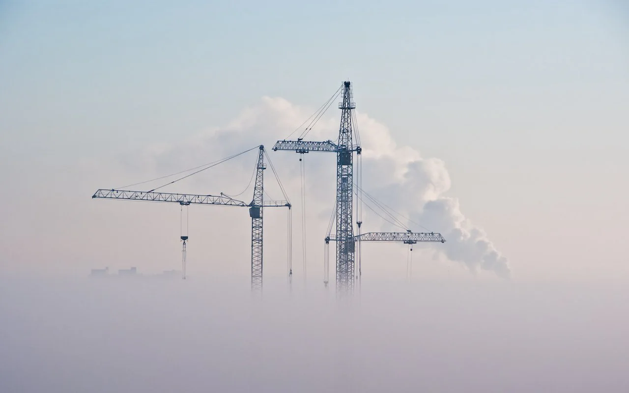 Construction cranes rising through fog, representing a temporary iCloud backup during a device transfer
