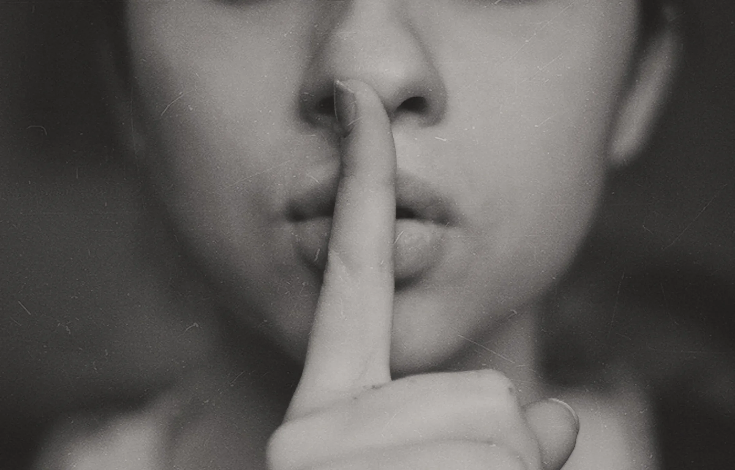 A person holding a finger to their lips as a reminder to keep passwords secret
