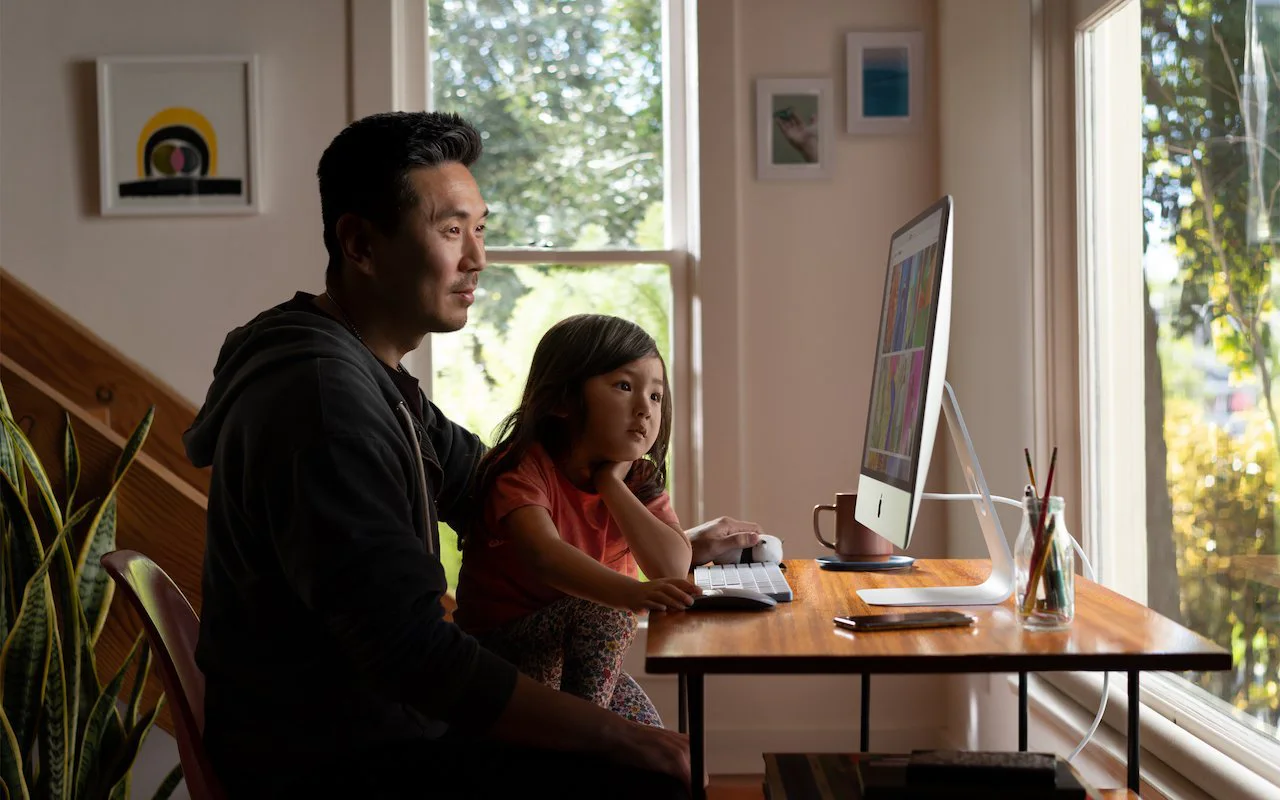 A parent and child using an iMac together at home