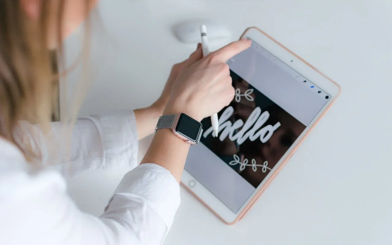 A person drawing the word Hello on an iPad with Apple Pencil