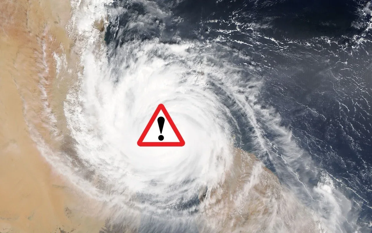 Satellite view of a hurricane with a warning symbol over its eye