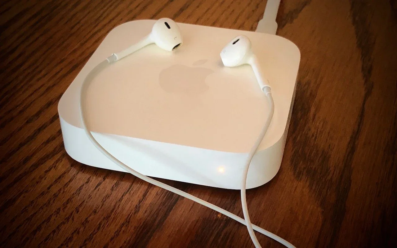 An Apple AirPort Express base station with a pair of AirPods resting on top