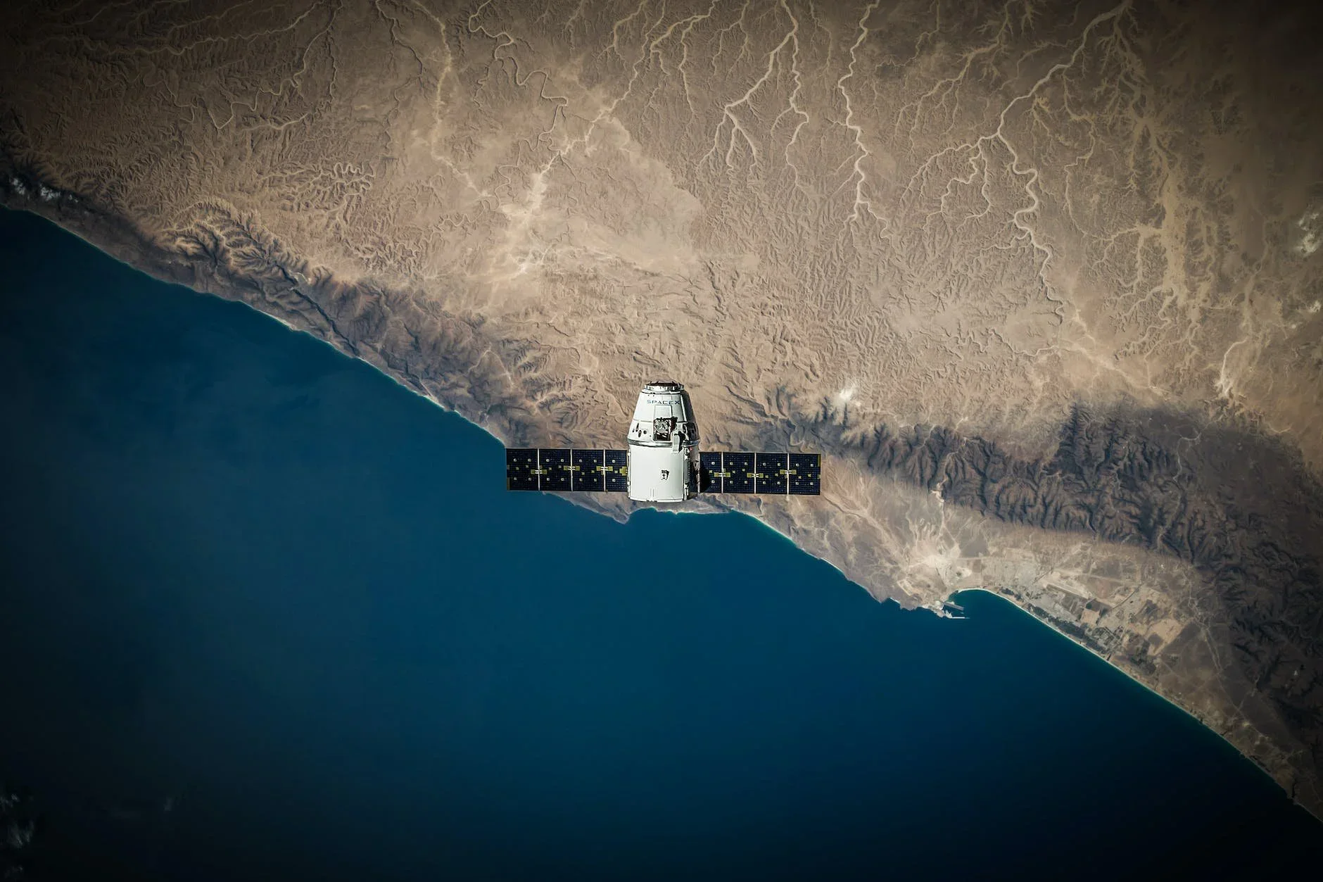 A satellite orbiting above the coast of Earth
