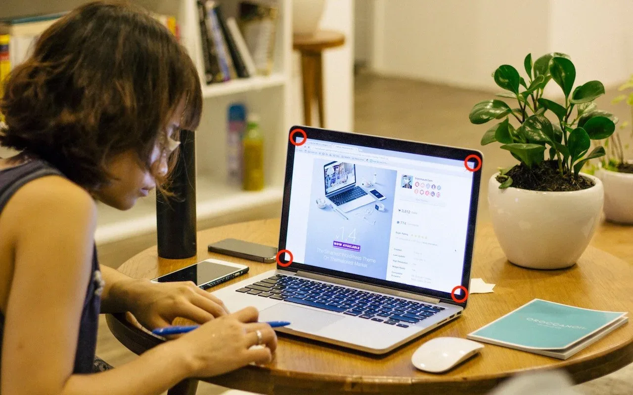 A person using a MacBook with all four screen corners highlighted