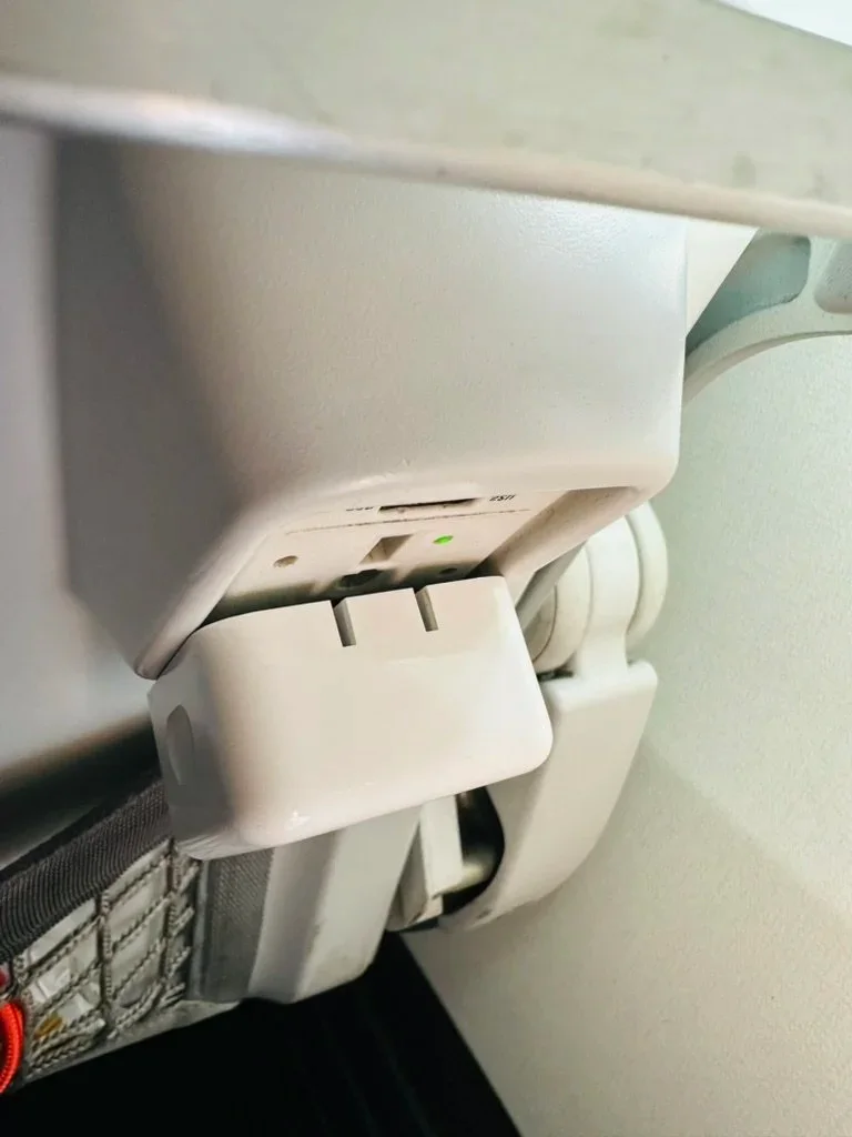 A MacBook Air Dual USB-C charger blocked by a recessed airplane outlet