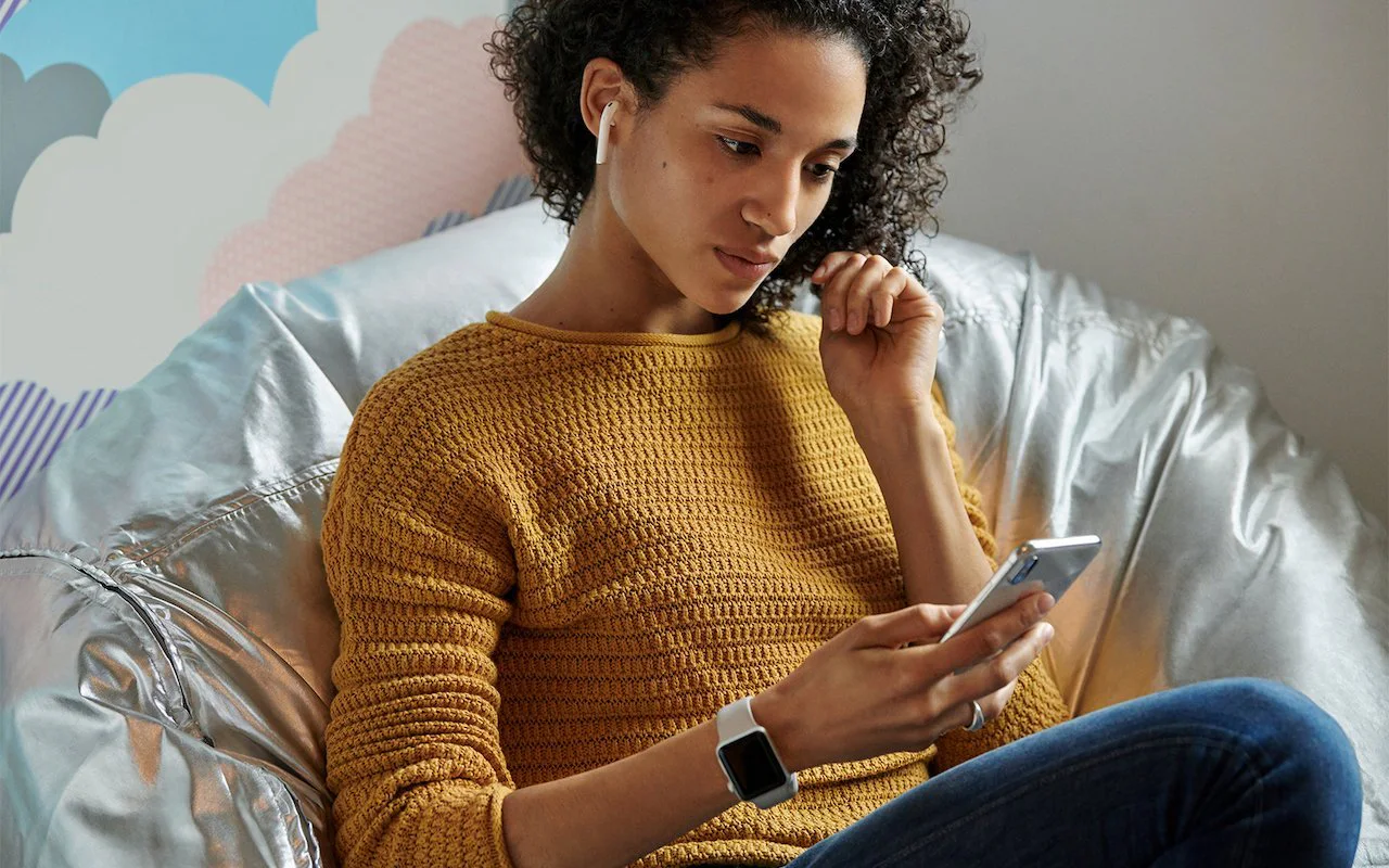 Woman wearing AirPods while looking at her iPhone