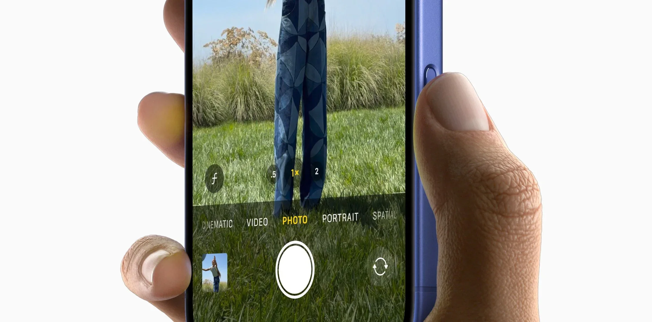 A hand holding an iPhone 16, thumb on the camera control button