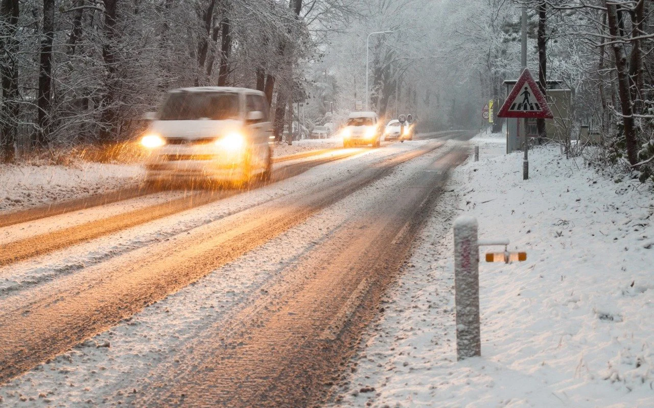 Cars driving along a snowy road during a winter storm