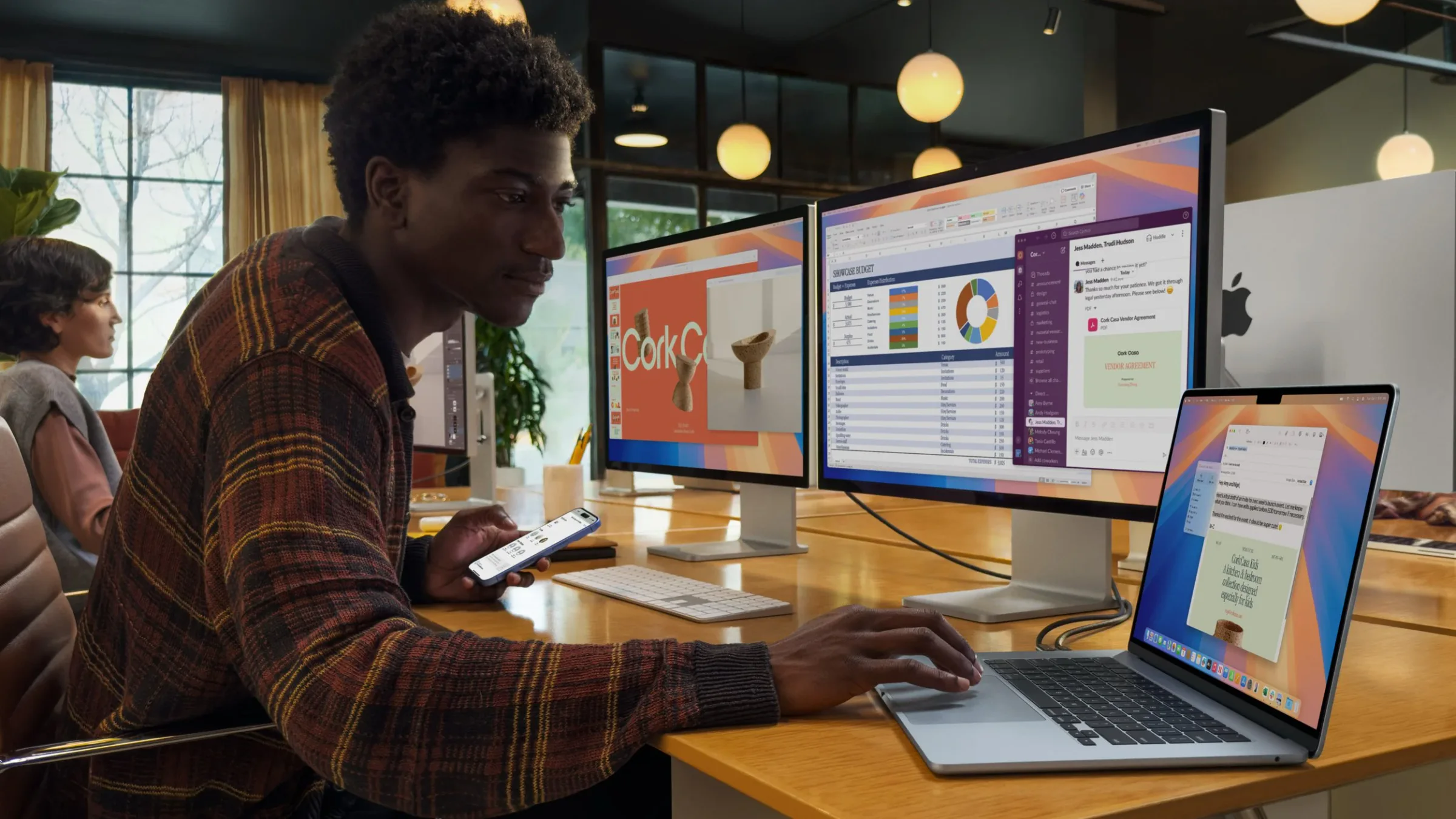 Person using a MacBook Air with two external displays