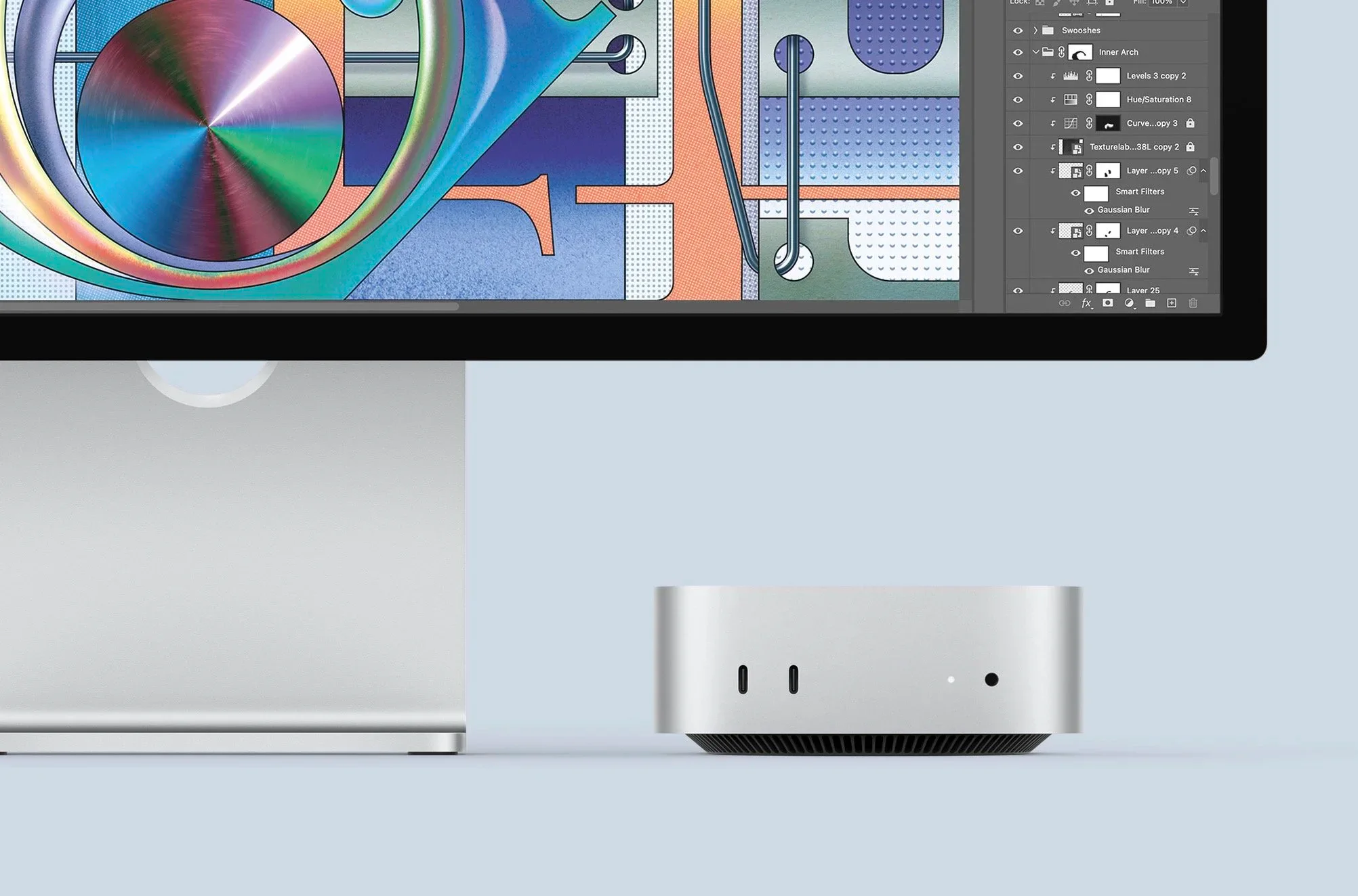 A silver M4 Mac mini beneath a colorful desktop display