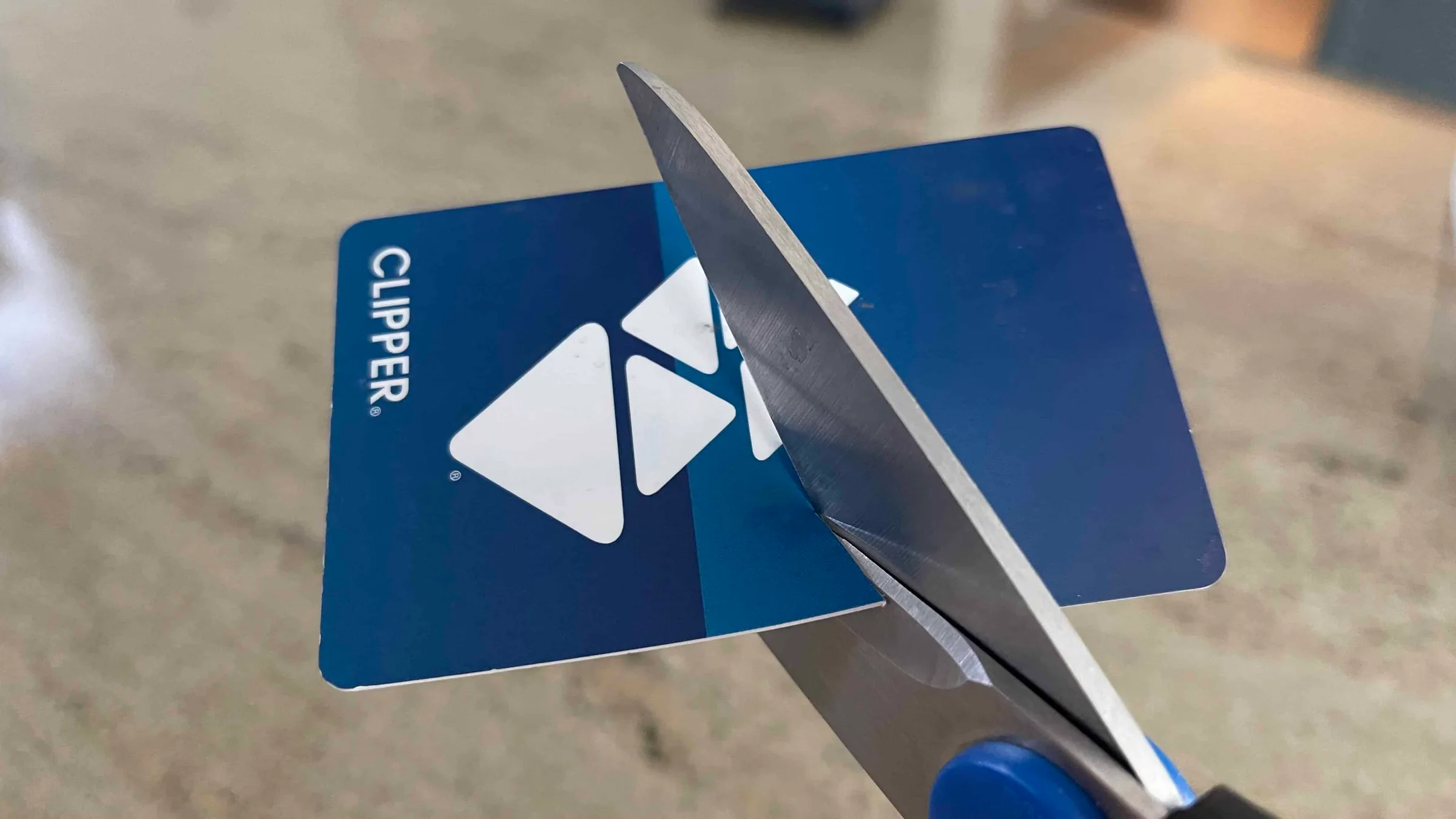 Scissors cutting through a plastic Clipper transit card