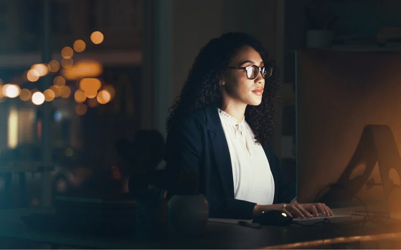 A woman working late on a laptop in a dark room