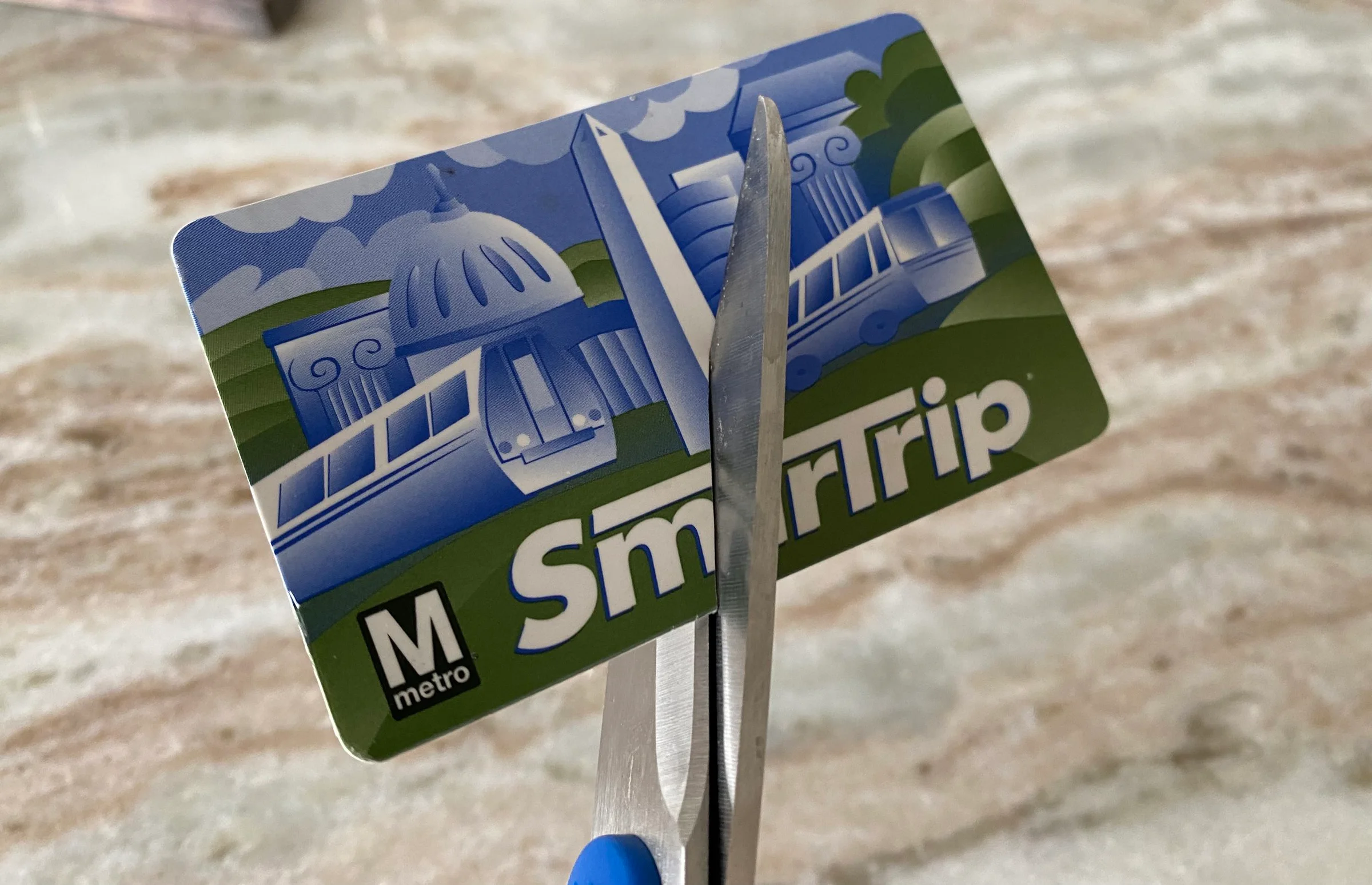 A plastic SmarTrip card being cut in half with scissors