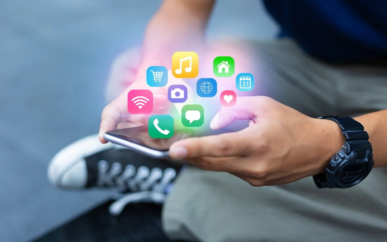 Hand holding a phone beneath floating app icons
